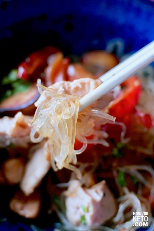 close up of kelp noodles and chicken on chopsticks