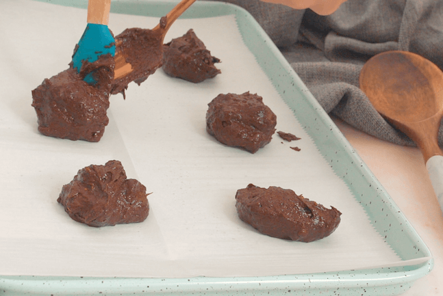 scooping chocolate cookie batter onto baking sheet