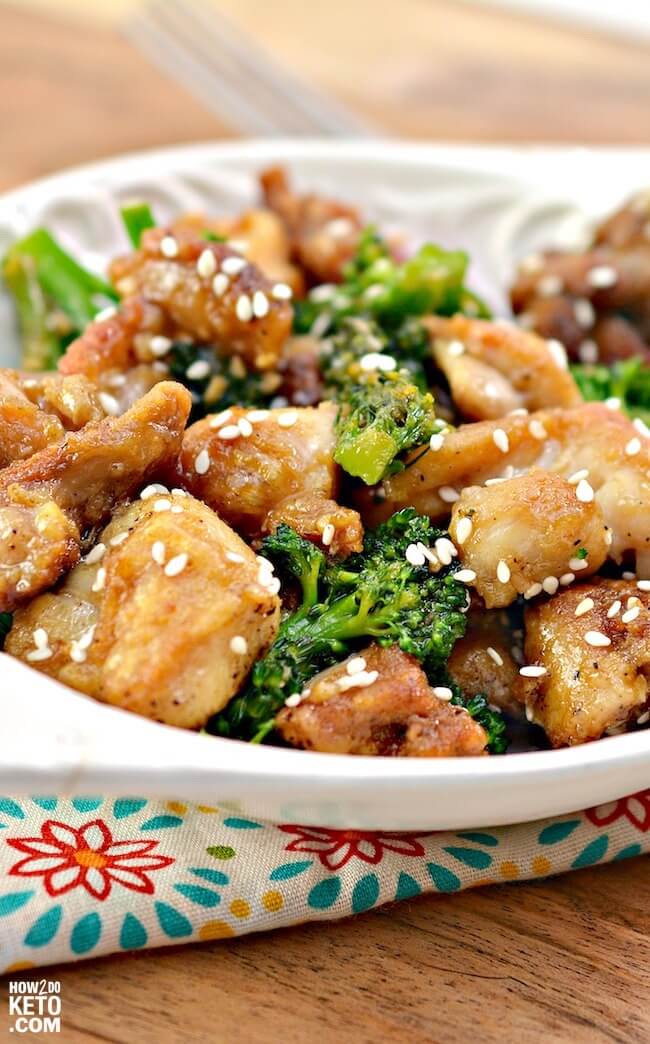 close up of crispy sesame chicken pieces, served with broccoli