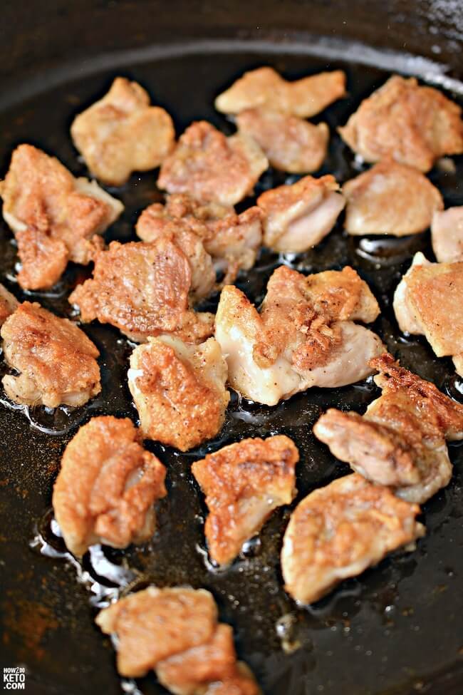 bite sized chicken pieces searing in a cast iron skillet