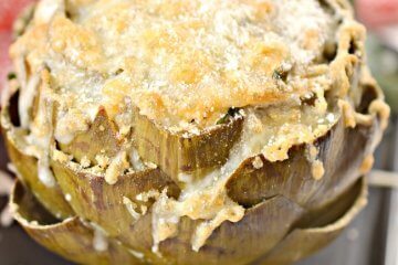 These keto-friendly stuffed artichokes are smothered in cheese and topped with crispy pork rind crumbles - they're so good they literally melt in your mouth!