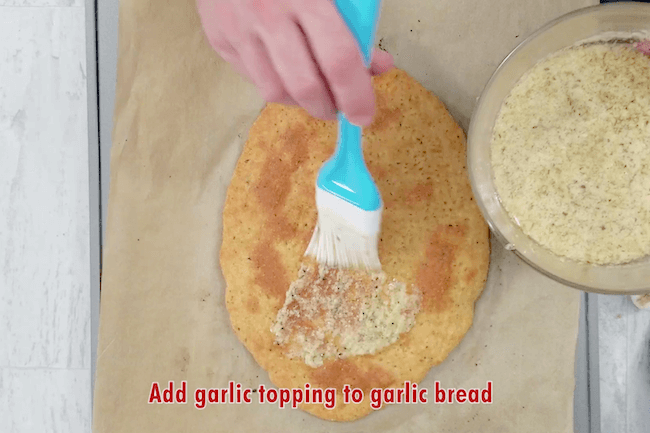 spreading garlic butter on baked keto bread