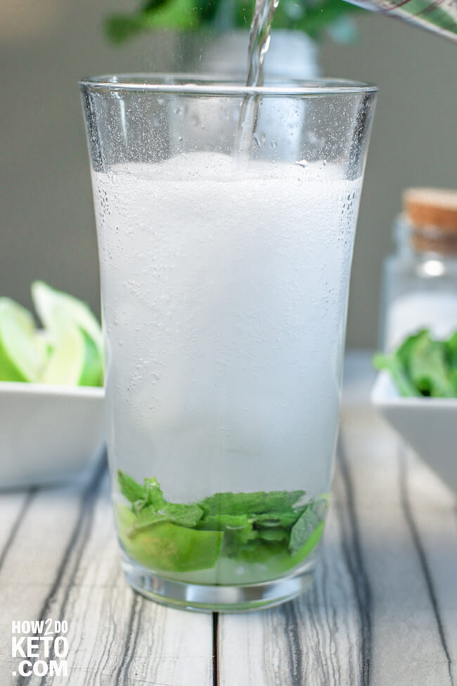 pouring sparkling water into a mojito glass