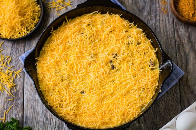 taco pie topped with shredded cheese in skillet