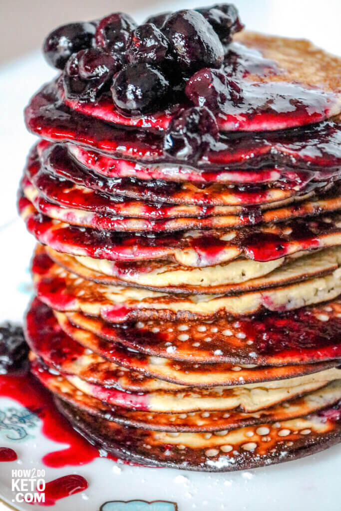 tall stack of almond flour pancakes topped with blueberry syrup