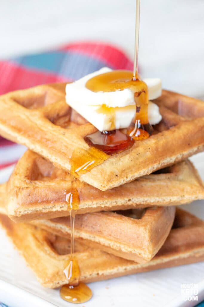 drizzling syrup on a stack of peanut butter keto waffles