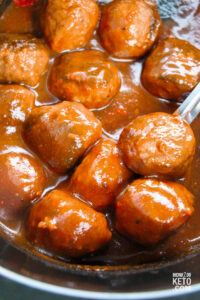 stirring meatballs in sauce in slow cooker