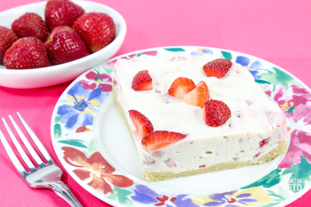 slice of strawberry cheesecake with a bowl of fresh strawberries
