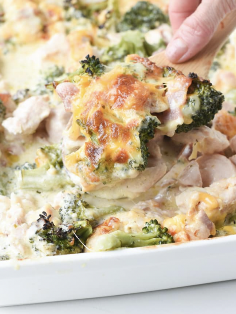 scooping cheesy chicken and broccoli casserole with wooden spoon