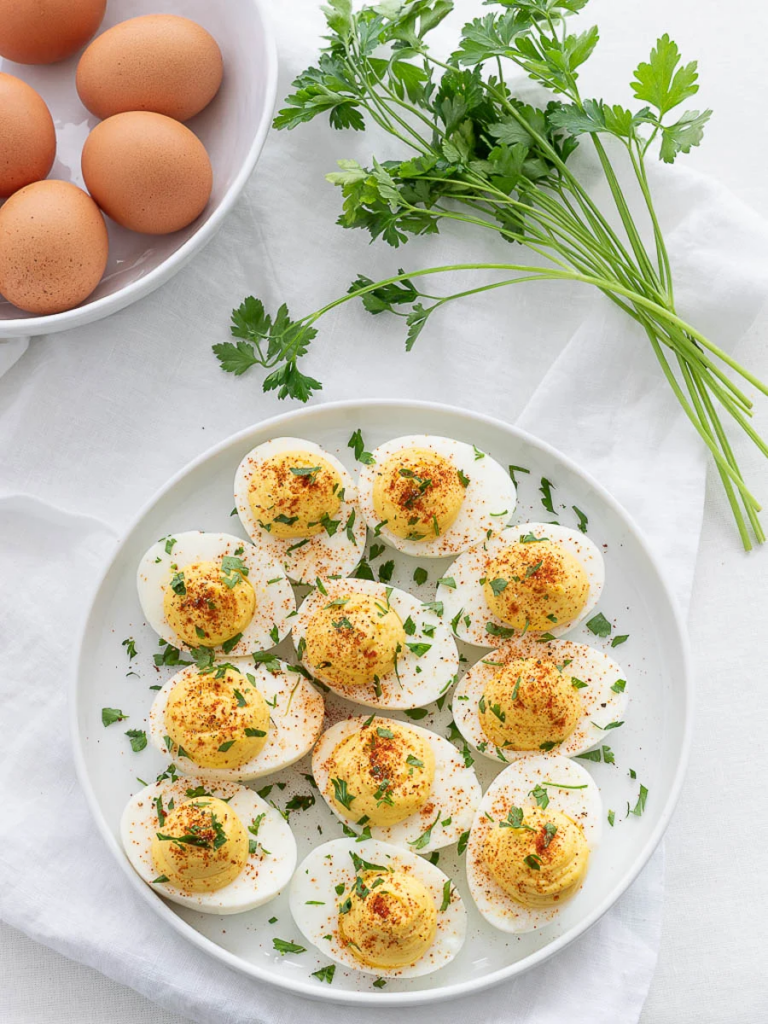 plate of deviled eggs with paprika and parsley