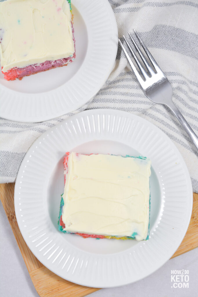 two slices of frosted rainbow cake, viewed from above